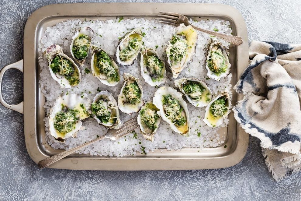 Oysters Rockefeller on a silver baking sheet.